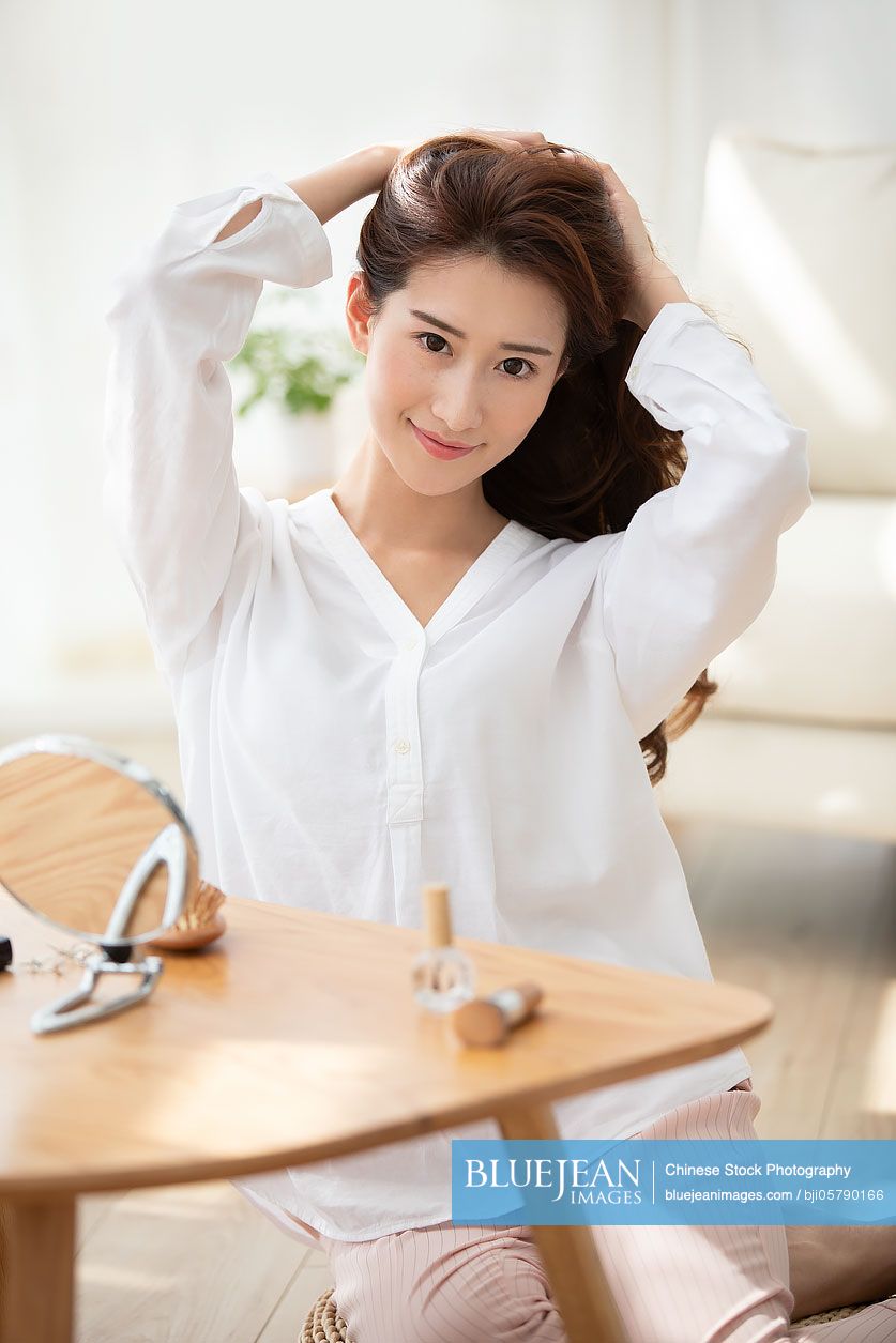 Young Chinese woman brushing hair at home