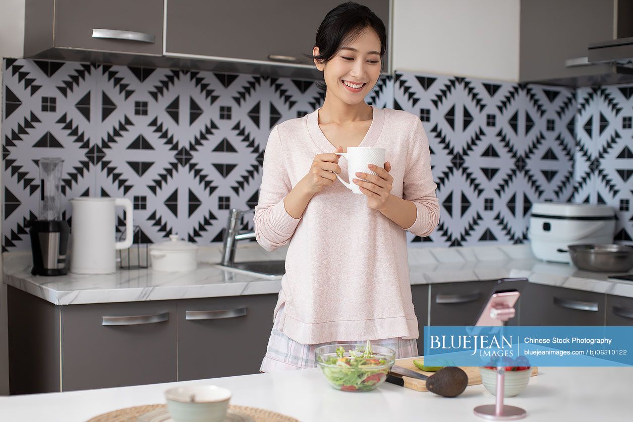 Happy young Chinese woman cooking in kitchen