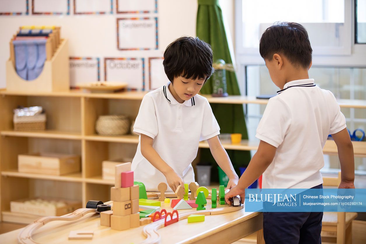 Little Chinese boys playing train set in classroom