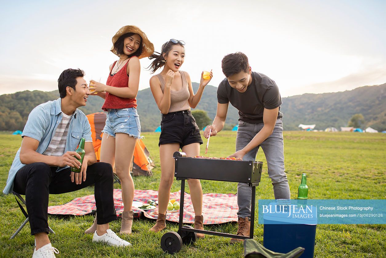 Happy young Chinese friends barbecuing outdoors