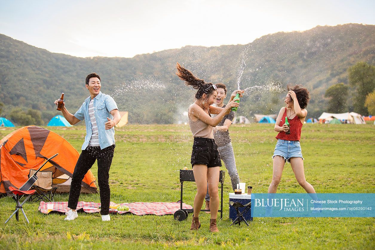 Happy young Chinese friends barbecuing outdoors