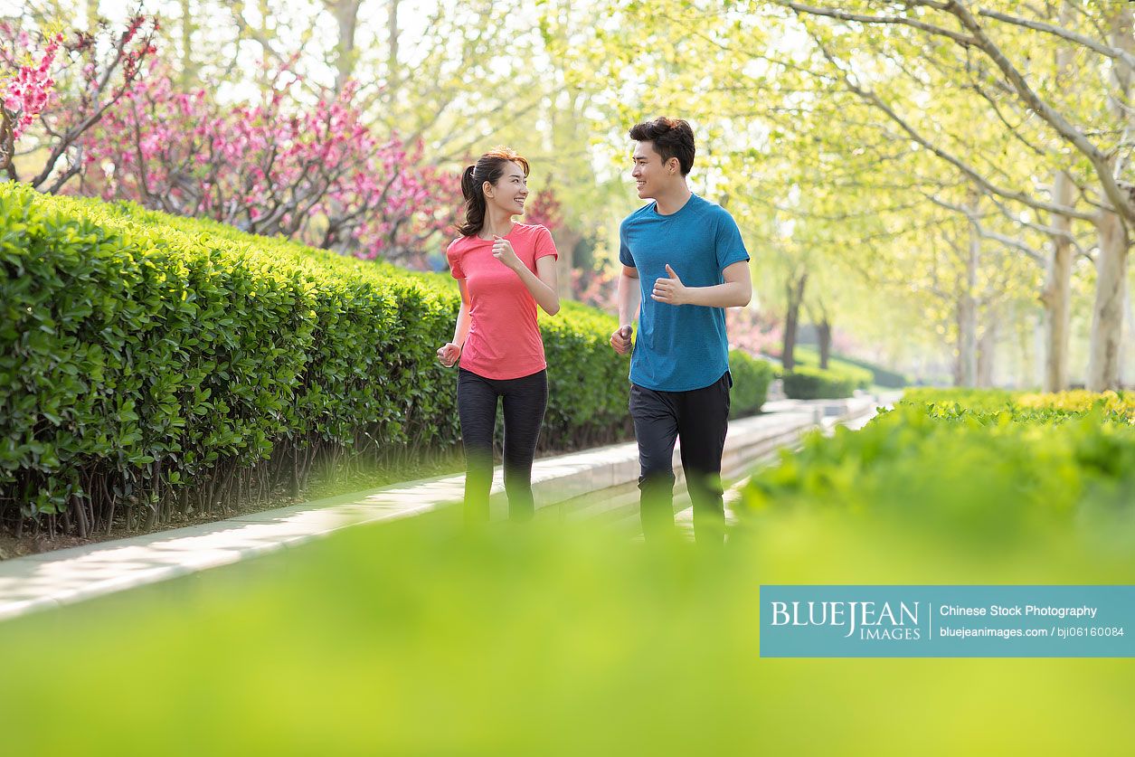 Happy young Chinese couple running in park