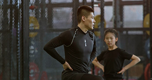 Active Chinese children having exercise class with their coach in gym,4K