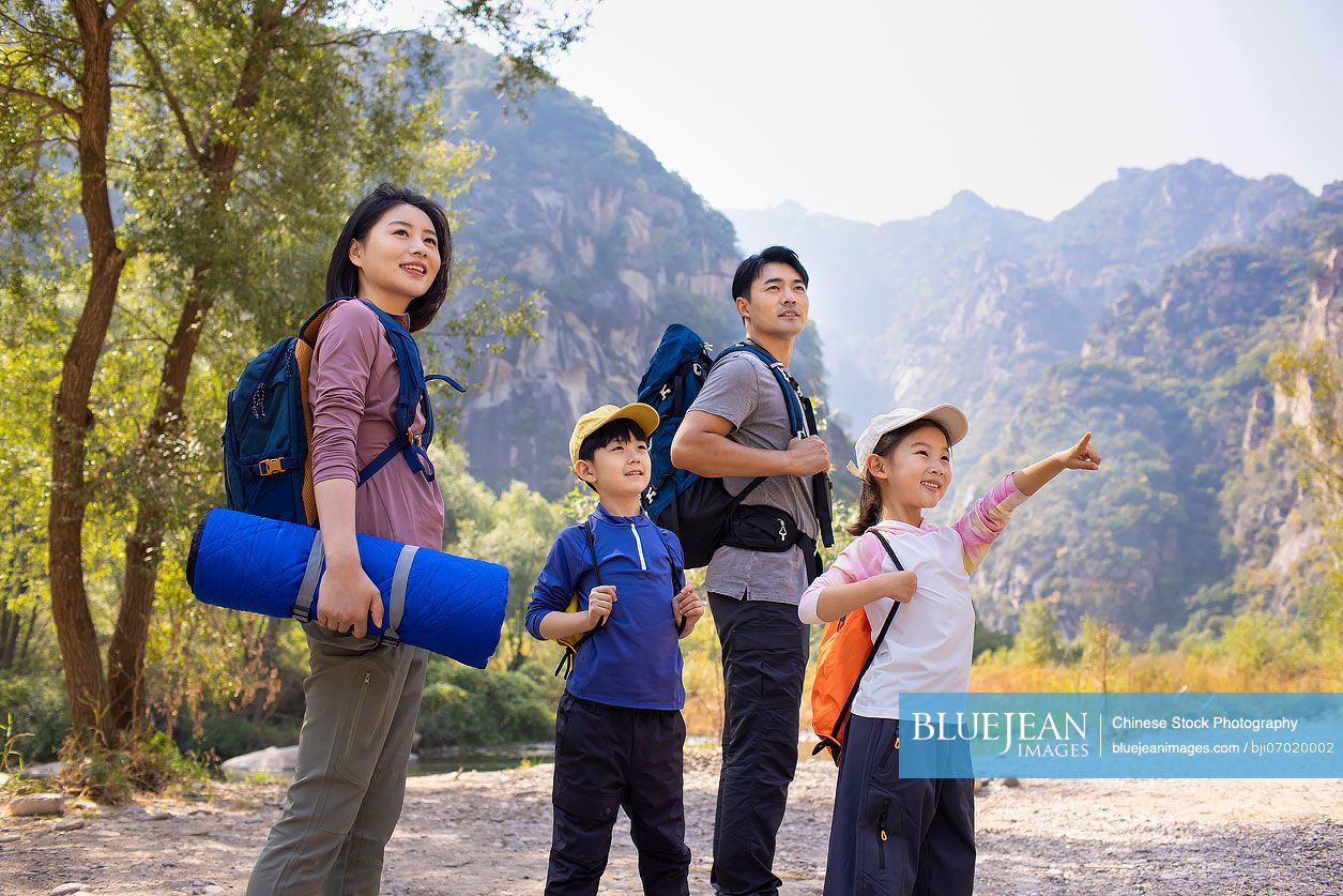 Happy young Chinese family hiking outdoors