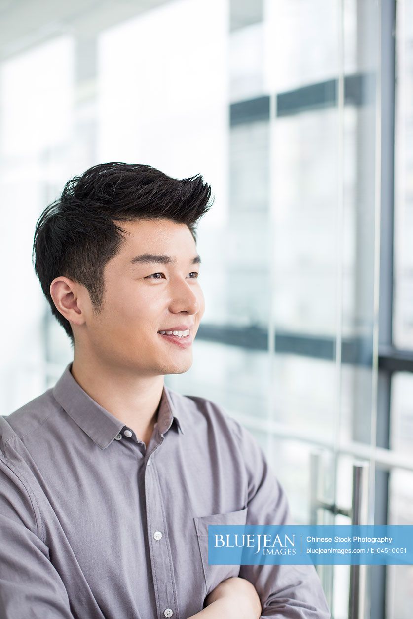 Young Chinese businessman thinking in office