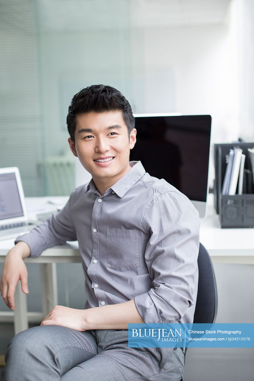 Young Chinese businessman thinking in office