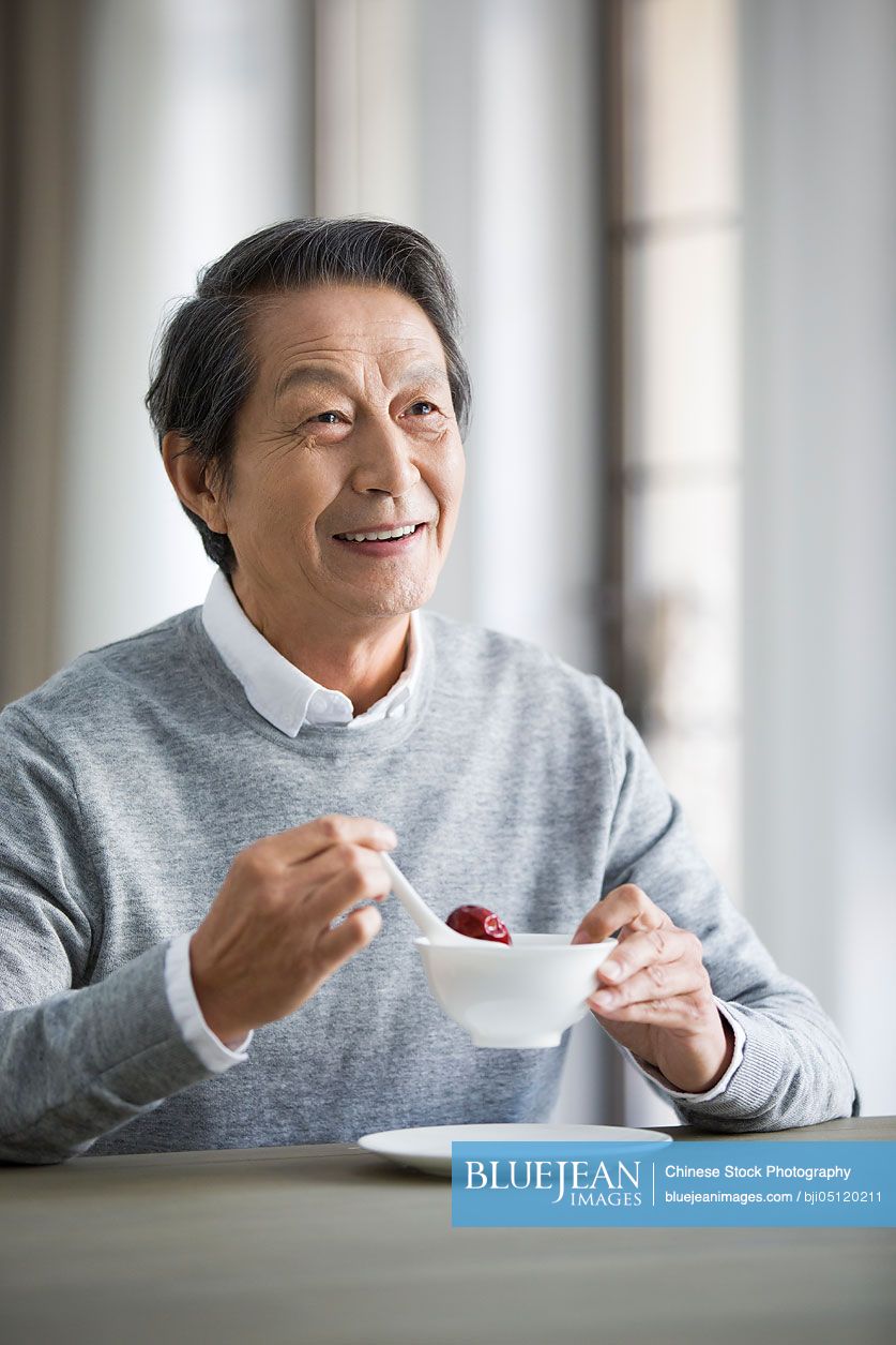 Senior Chinese man eating nutritious porridge