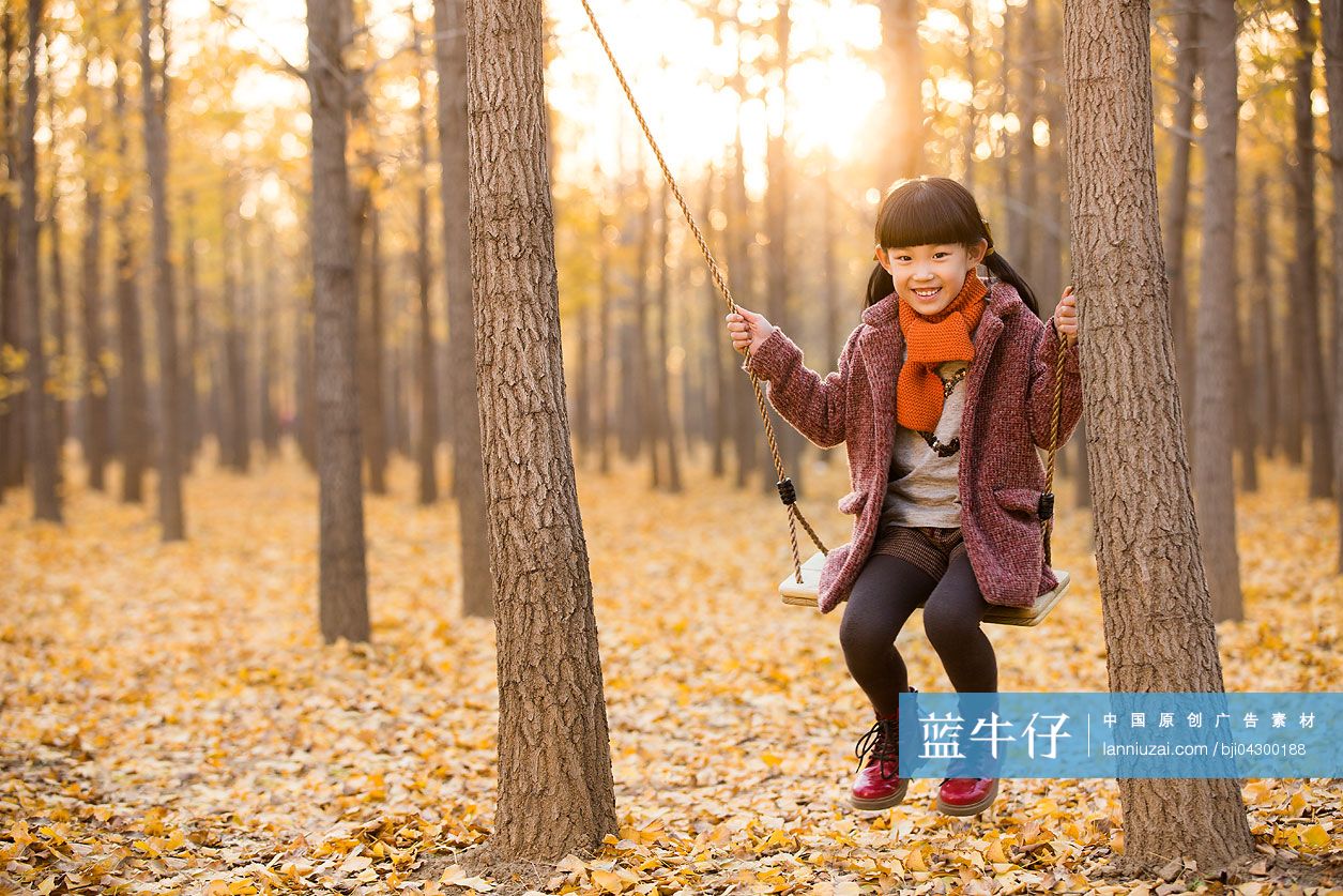 小女孩在秋日树林荡秋千