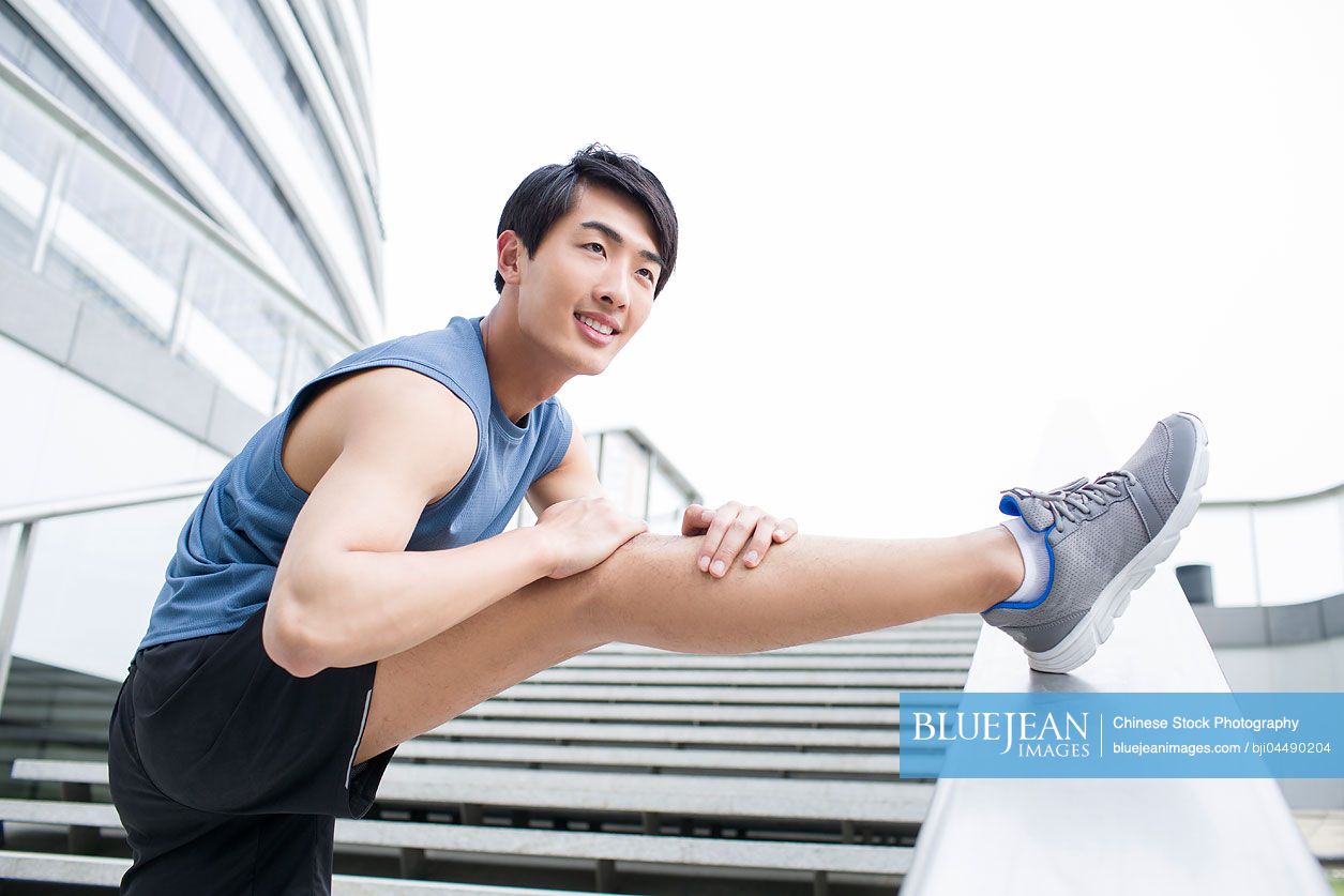 Young Chinese man stretching leg