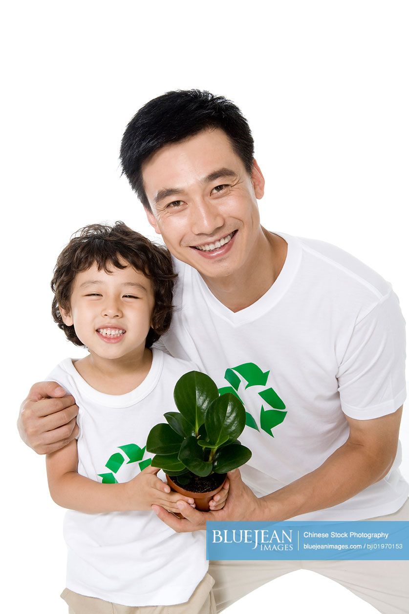 Little Chinese boy with his father holding a potted plant