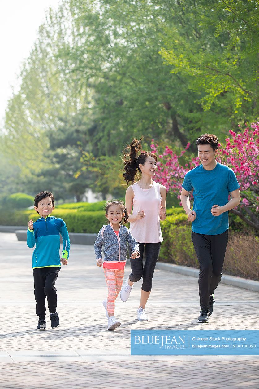Happy young Chinese family running in park