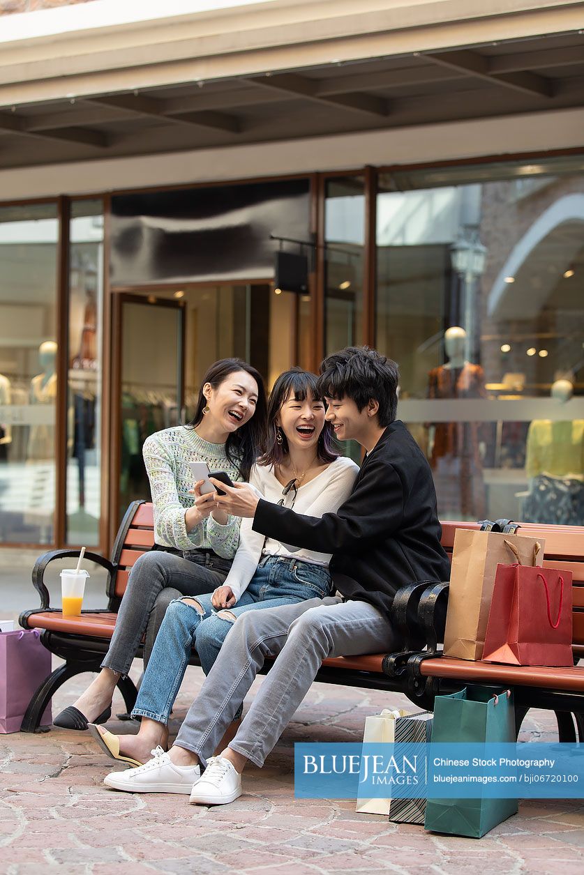 Happy young Chinese friends using smart phone