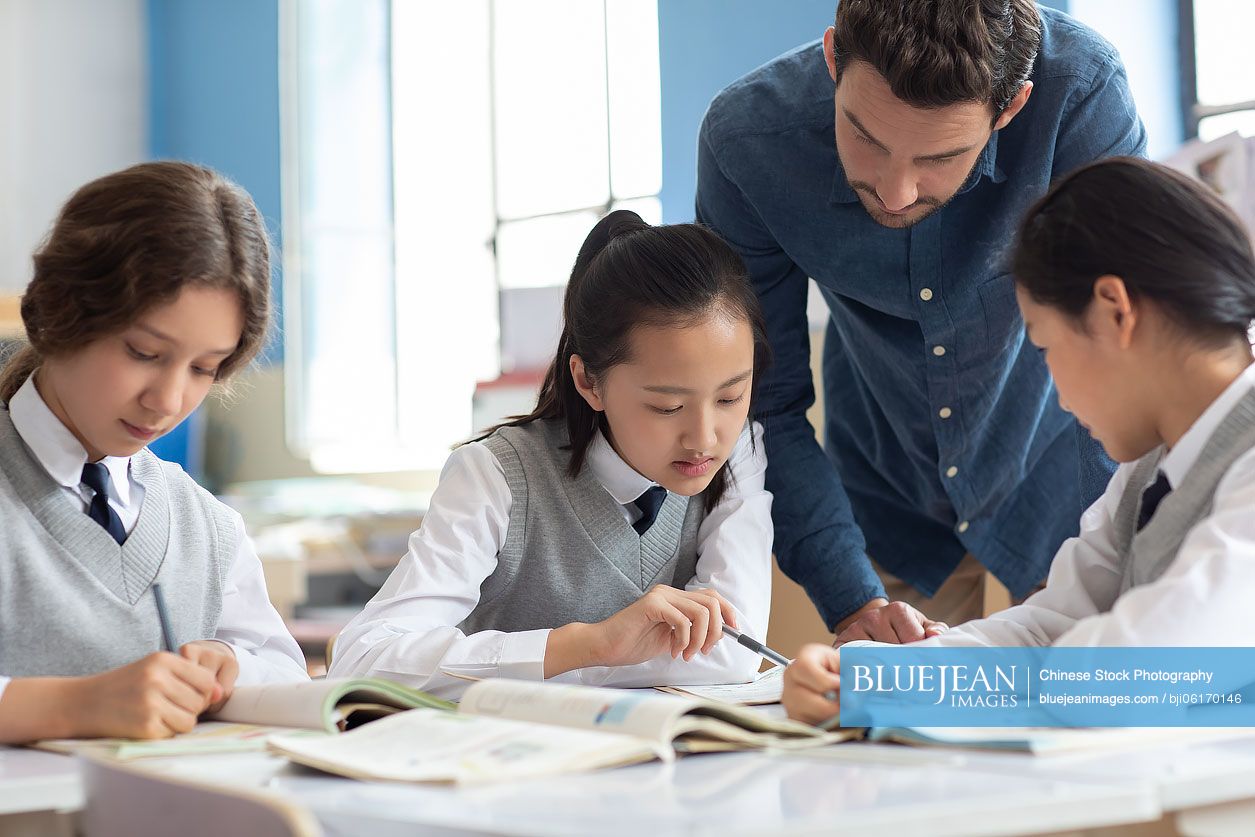 Young teacher helping students in classroom