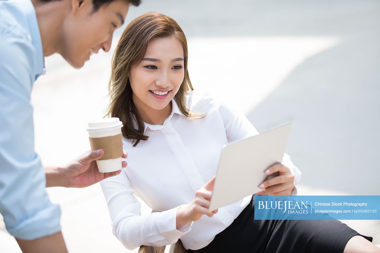 Young Chinese business people using digital tablet outdoors