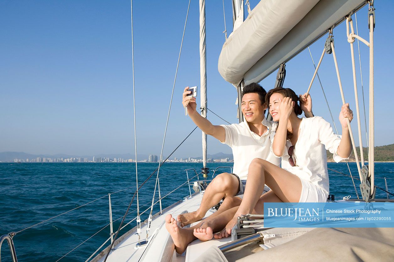 Happy Chinese couple taking self portrait on the boat deck