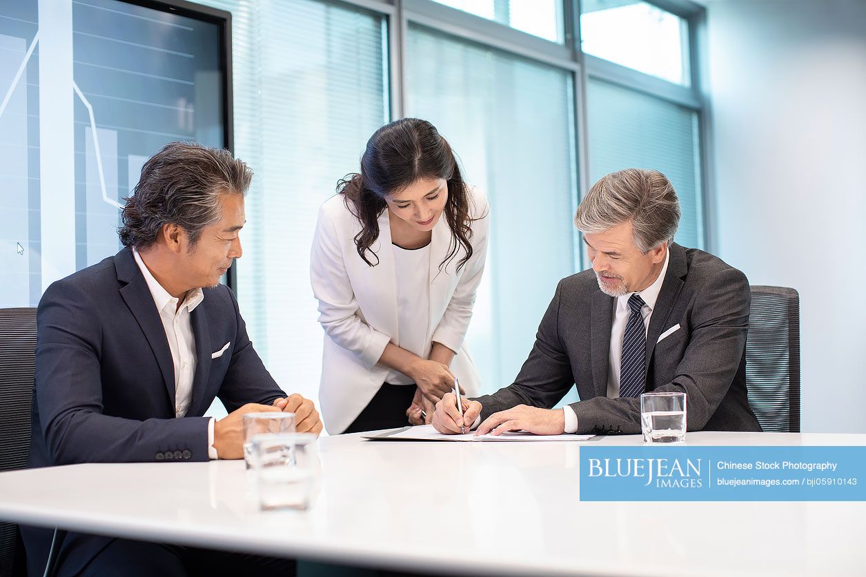 Business people signing contract in conference room