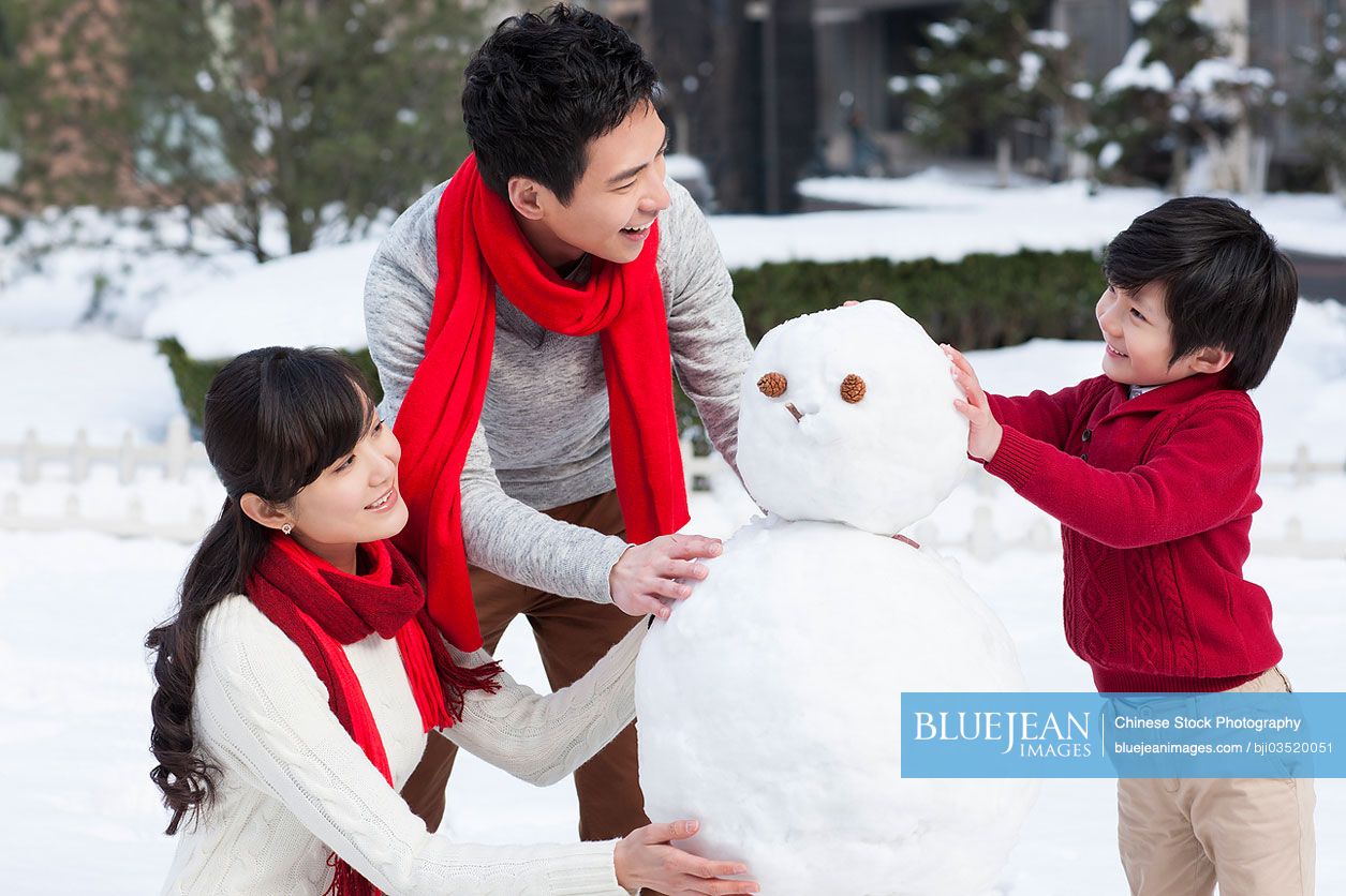 Happy Chinese family building snowman