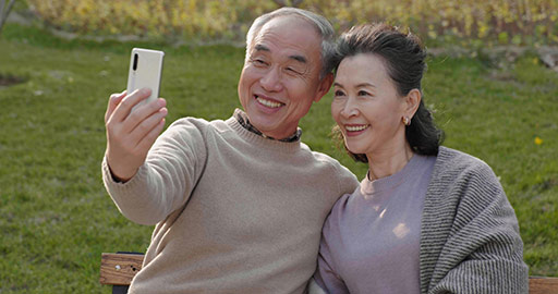 Cheerful senior Chinese couple using smart phone in the park,4K