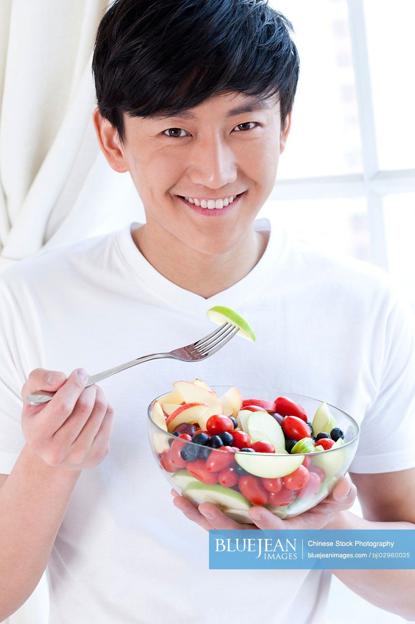 Young Chinese man eating fruit salad