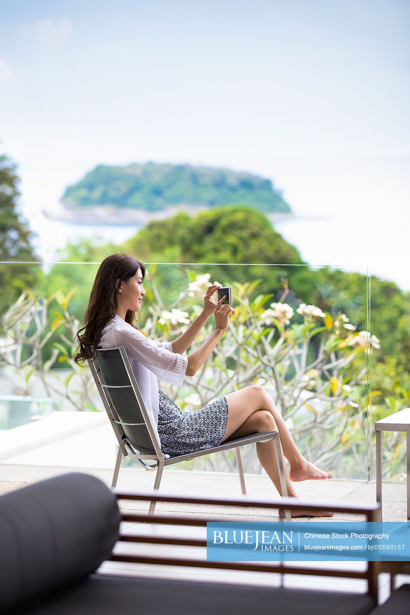Happy young Chinese woman relaxing on balcony