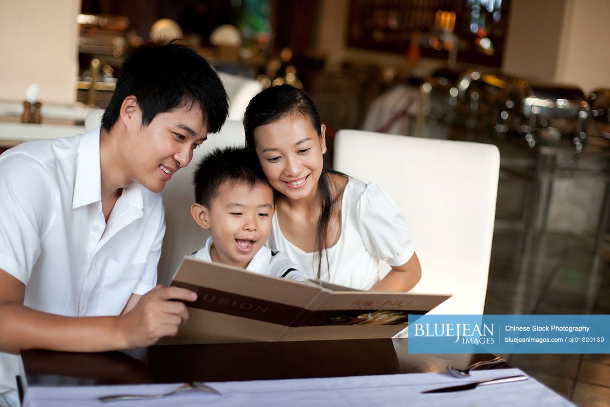 Portrait of a happy Chinese family looking through a menu