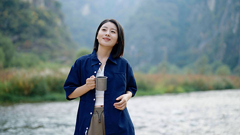 Cheerful young Chinese woman enjoying the beautiful natural scenery