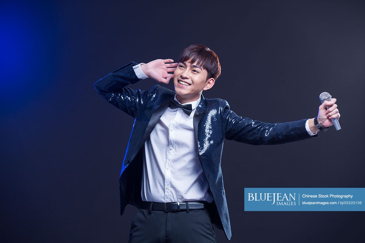 Young Chinese man singing with microphone