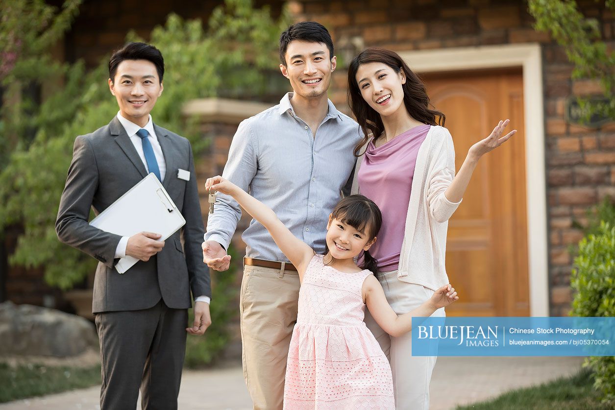 Happy young Chinese family holding keys to new house