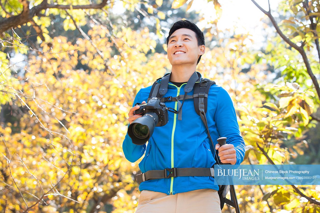 Young male Chinese hiker with SLR camera