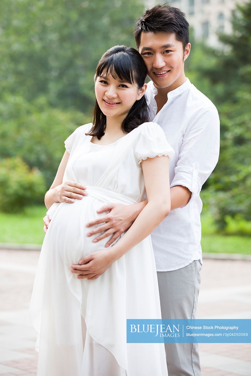 Young Chinese man embracing pregnant wife
