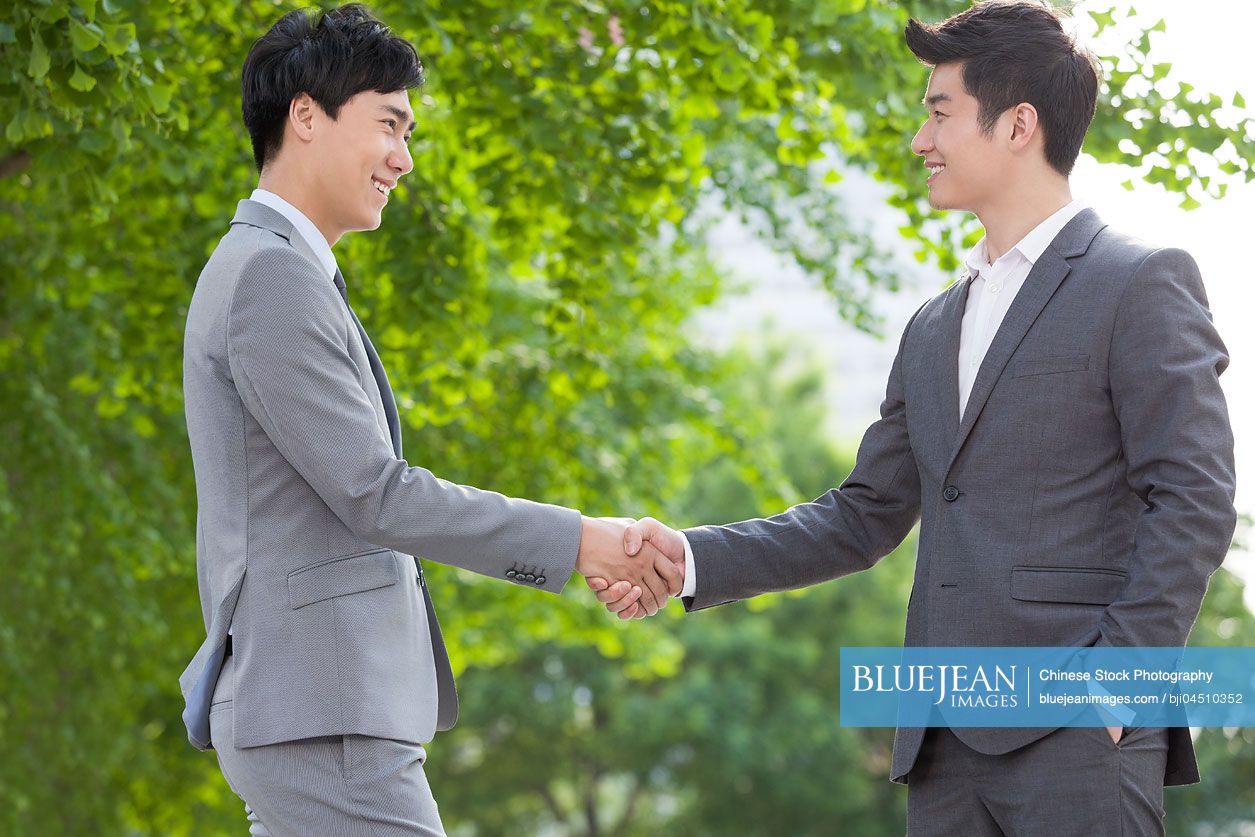 Young Chinese business person shaking hands outdoors