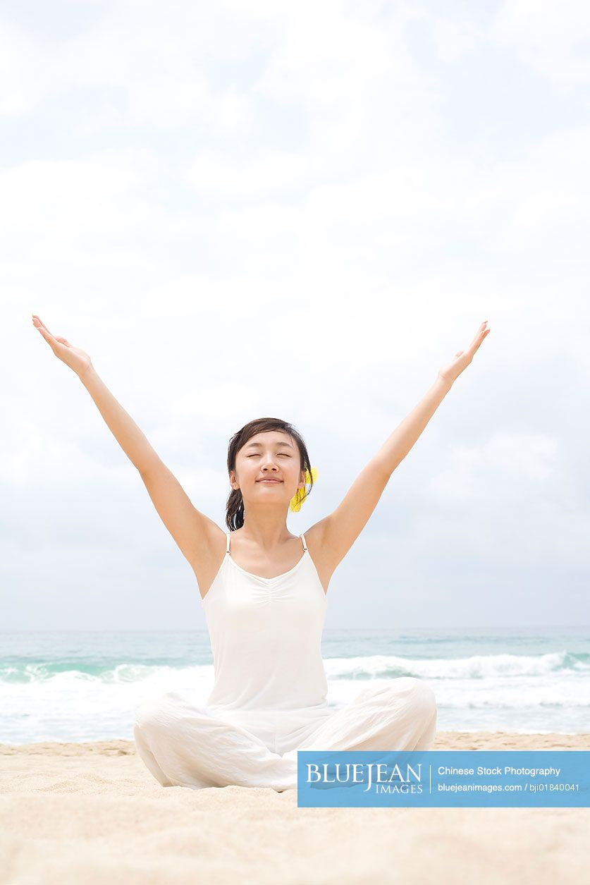 A woman practicing yoga at the beach