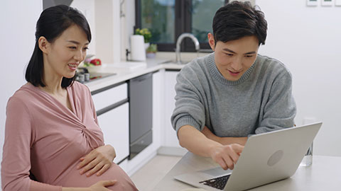 Young pregnant Chinese couple shopping on internet