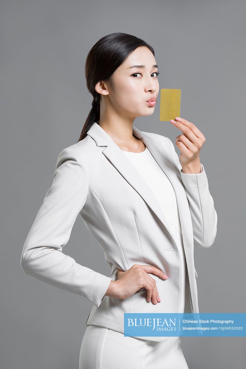 Happy young Chinese businesswoman holding a credit card