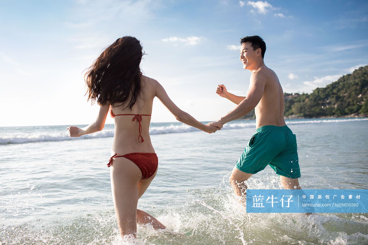 快乐的年轻情侣在海水里奔跑