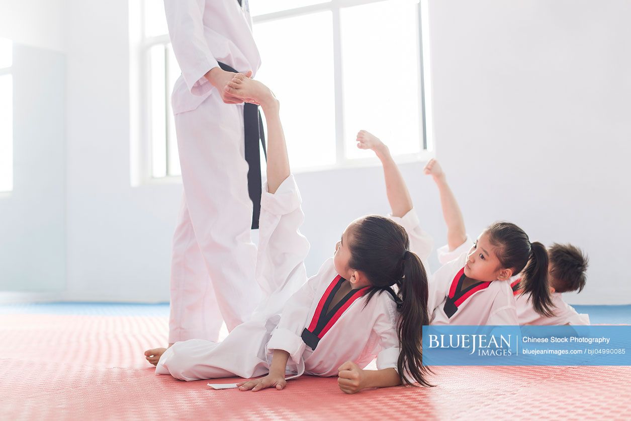 Young Chinese instructor teaching children Tae Kwon Do