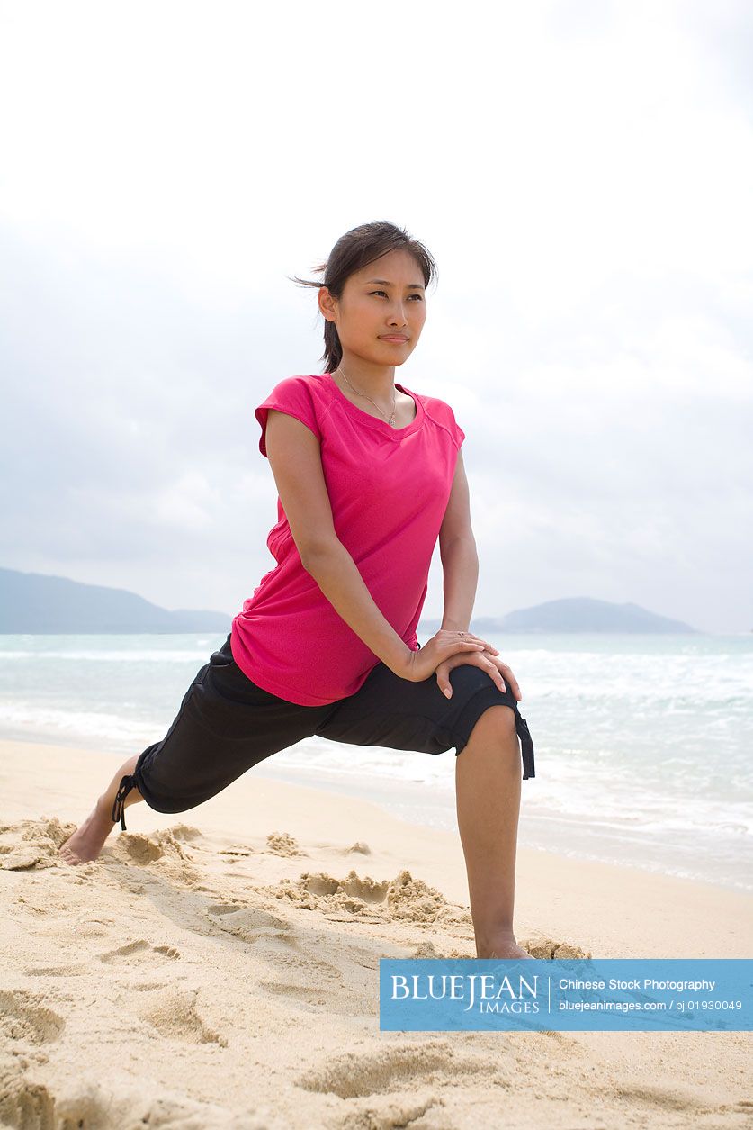 Young Chinese woman stretching by the sea