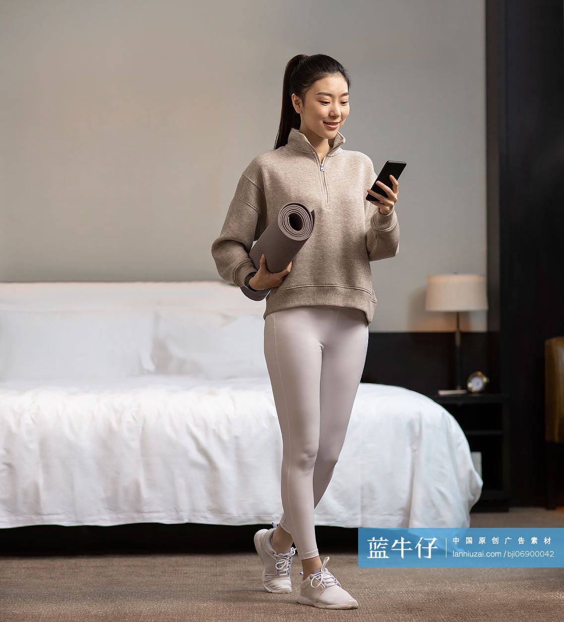 年轻女子拿着瑜伽垫和手机