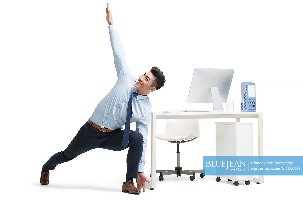 Young Chinese businessman exercising in office