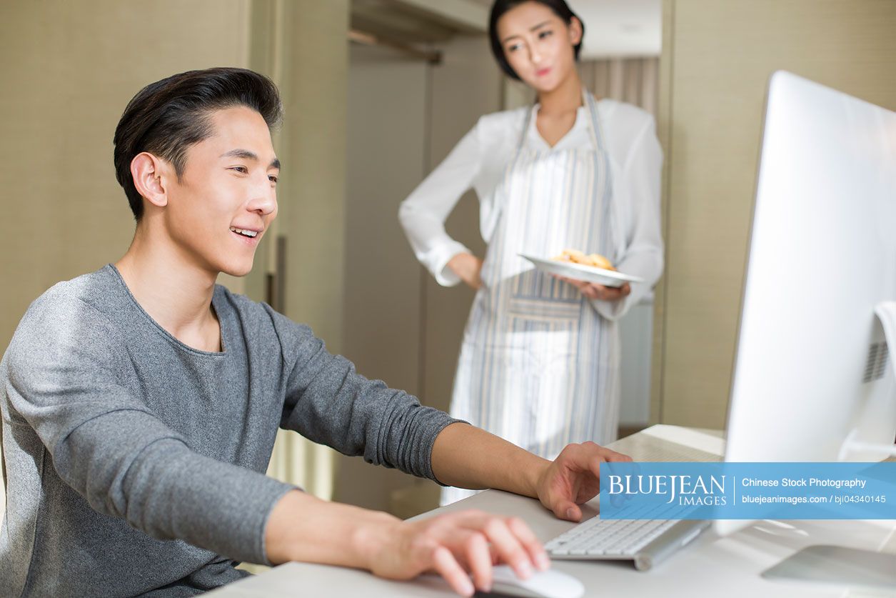 Young Chinese man working at home with his wife serving dim sum