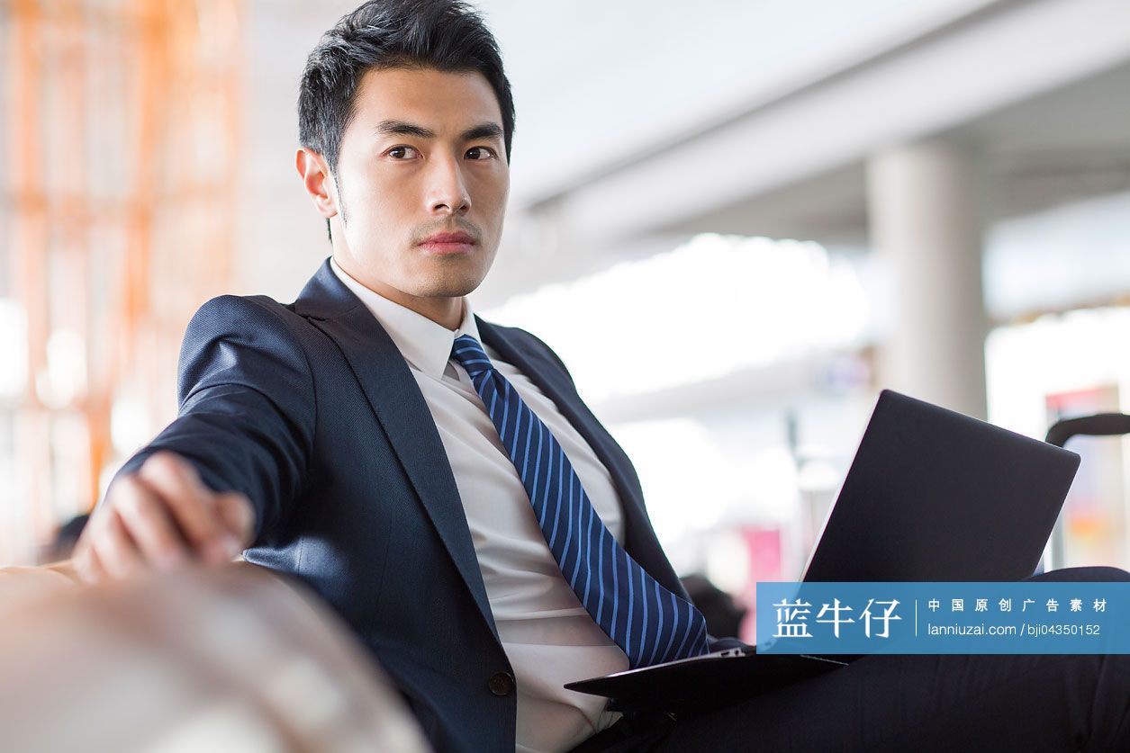 年轻商务男士在机场使用笔记本电脑