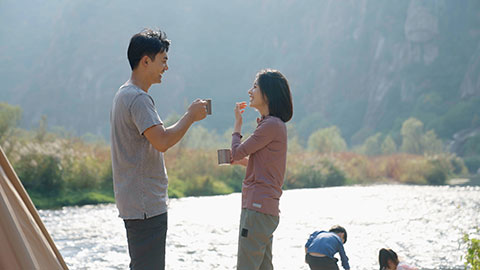 Happy young Chinese family camping outdoors