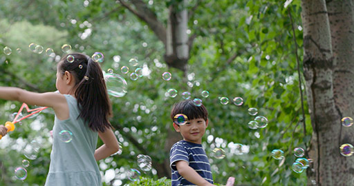 Three Chinese children blowing bubbles on grass,4K