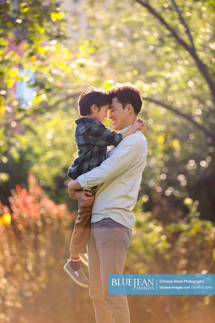 Happy Chinese father and son relaxing in park
