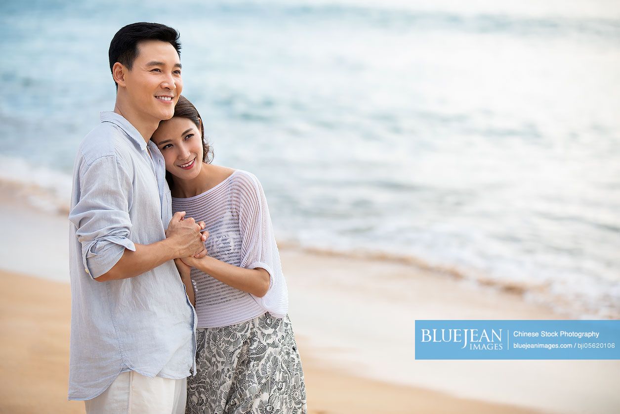 Happy young Chinese couple embracing on beach