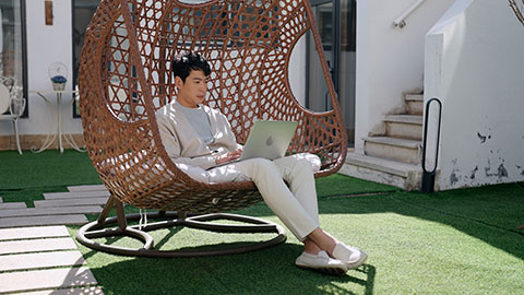 Happy mid adult Chinese man using laptop on hanging-chair,4K