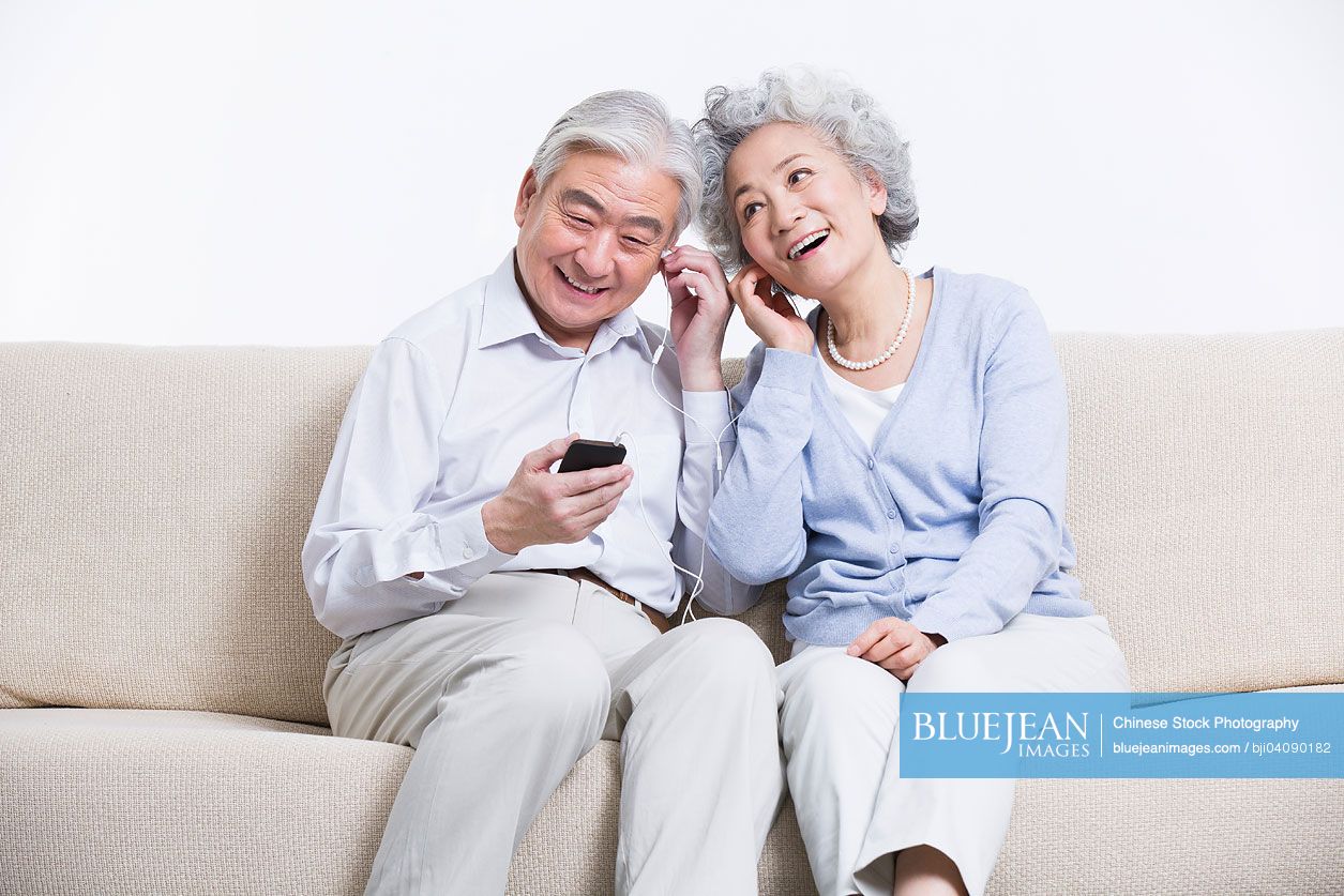 Senior Chinese couple enjoying music in living room
