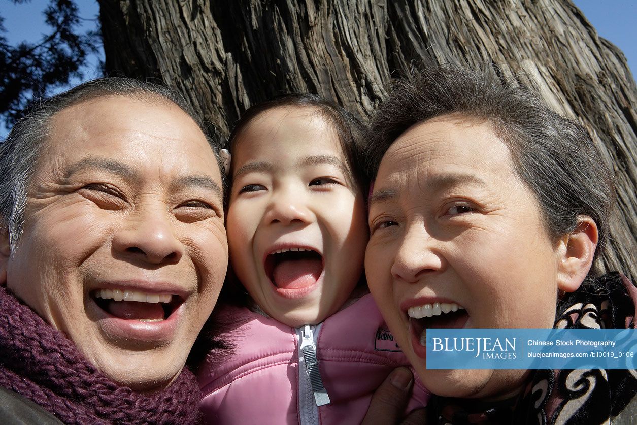 Chinese Grandparents And Their Granddaughter Smiling And Laughing