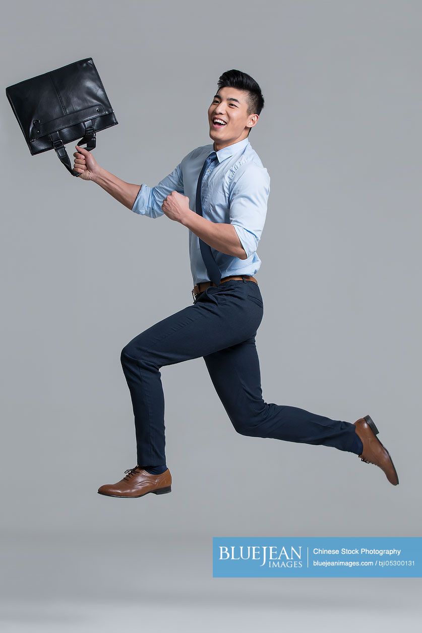 Cheerful young Chinese businessman punching the air