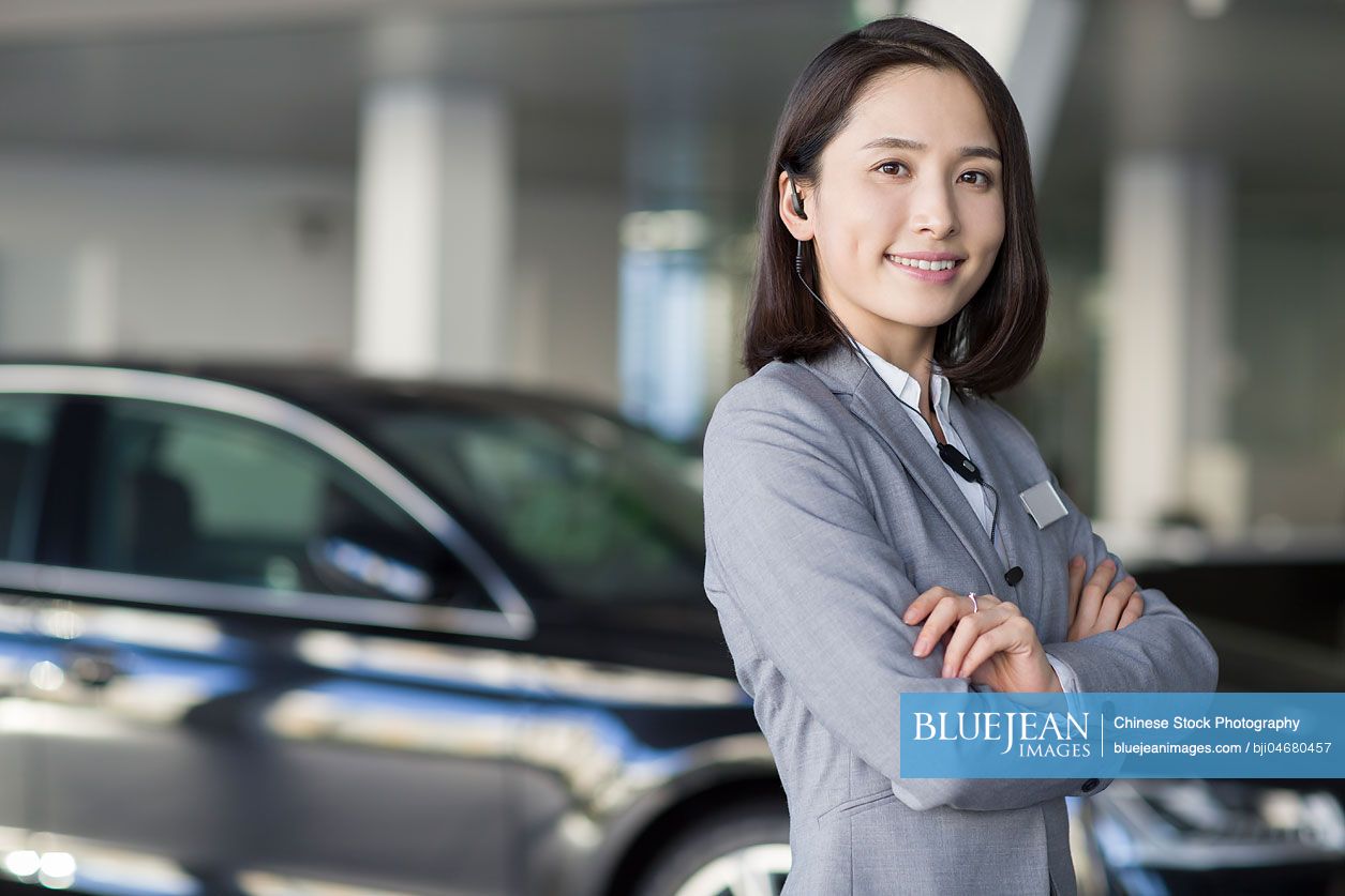 Confident Chinese car saleswoman with headset